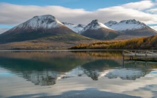 Vista das montanhas com neve e árvores em cores de outono refletidas em um lago calmo em Ushuaia durante abril.