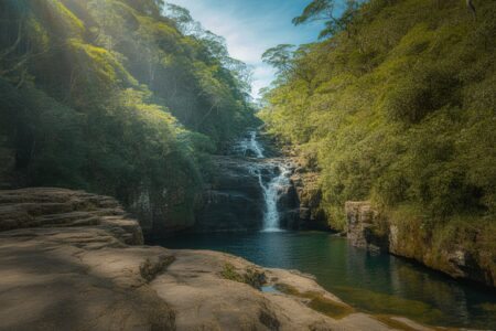 Cachoeira da Toca com água caindo de penhascos rochosos cercados por vegetação tropical densa e um lago azul cristalino abaixo.