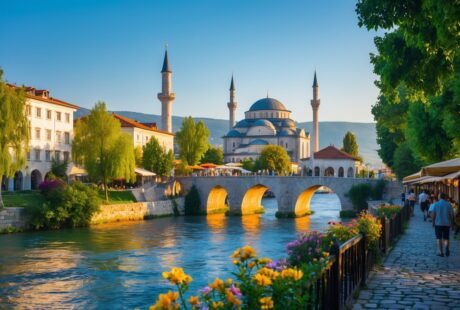 Vista da cidade de Prizren com a ponte sobre o rio, edifícios históricos, mesquita ao fundo e pessoas caminhando nas ruas.