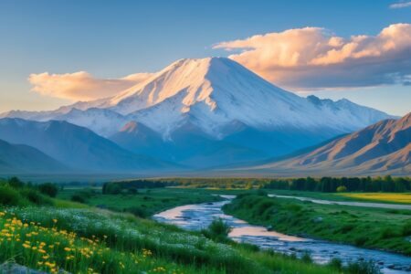 Vista do Monte Ararat com picos cobertos de neve, um vale verde com flores silvestres e um rio serpenteando sob um céu claro ao amanhecer.